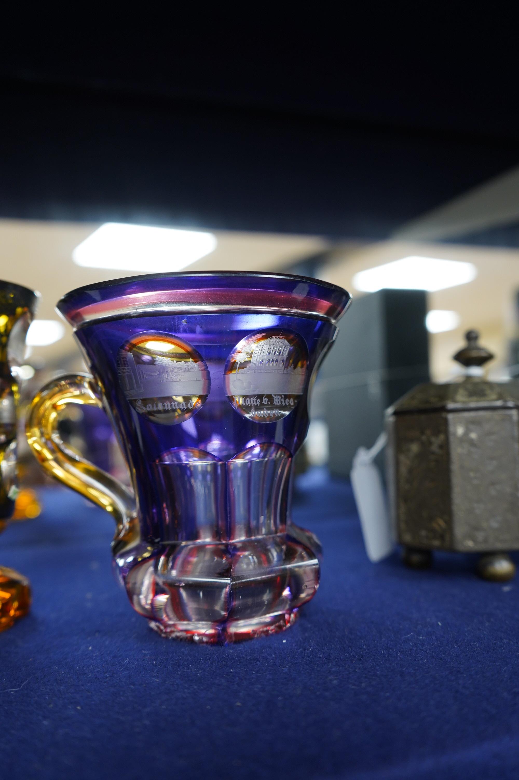 A 19th century Bohemian overlaid glass vase engraved with topographical views and a similar cup. Condition - good.